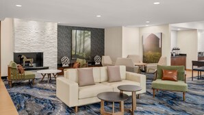 Un hall d’hôtel moderne doté d’une cheminée, de sièges confortables et d’une grande fenêtre.