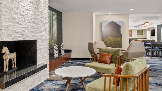 Un hall d’entrée avec un mur en pierre, une cheminée, un coin salon avec des canapés et des fauteuils, et un grand tableau accroché au mur.