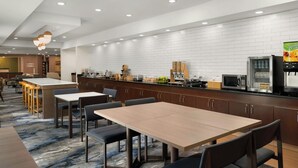 Une cuisine d’hôtel moderne, dotée d’un long comptoir, de divers appareils et d’un espace pour que les clients puissent s’asseoir.