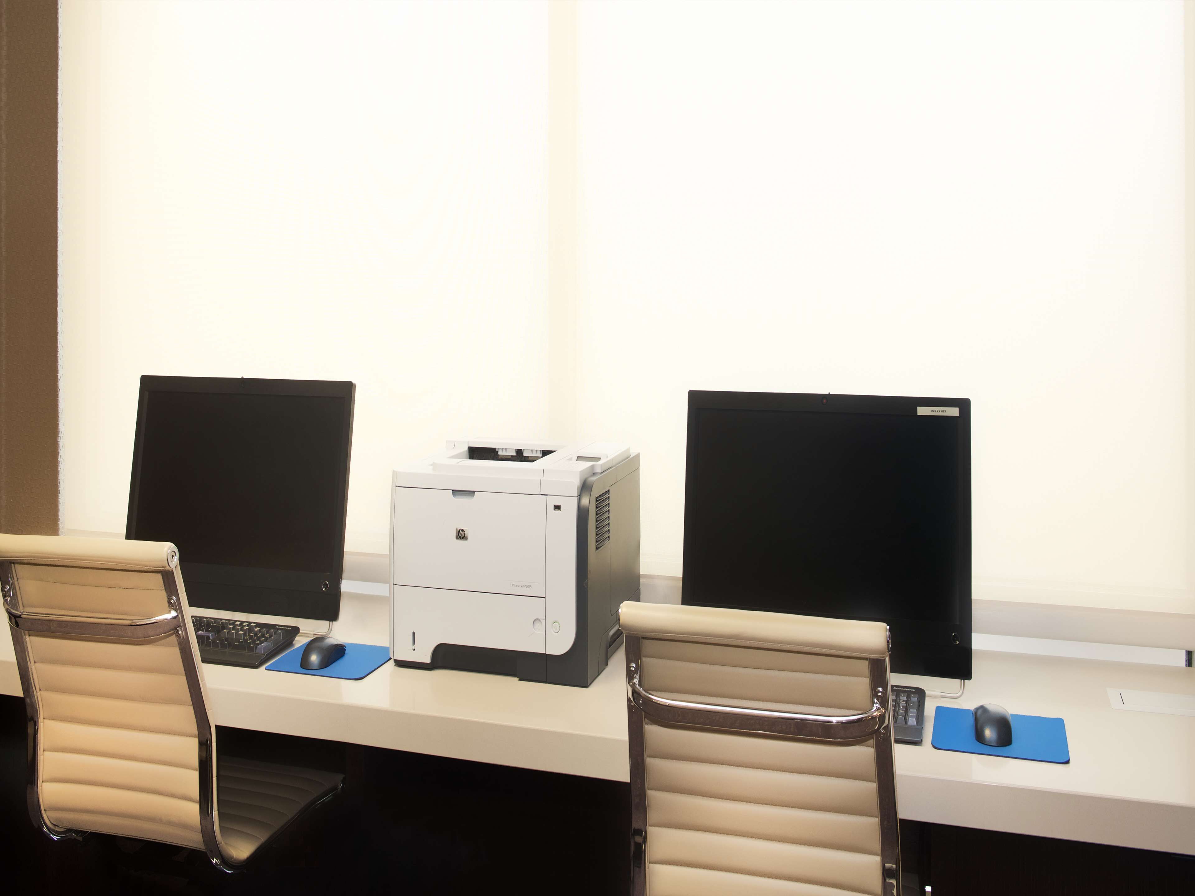 A workspace with two computers, a printer, and two chairs.