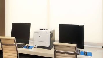 A workspace with two computers, a printer, and two chairs.