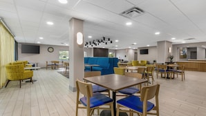 A spacious indoor area with multiple seating arrangements, including tables and chairs, and a blue sofa.
