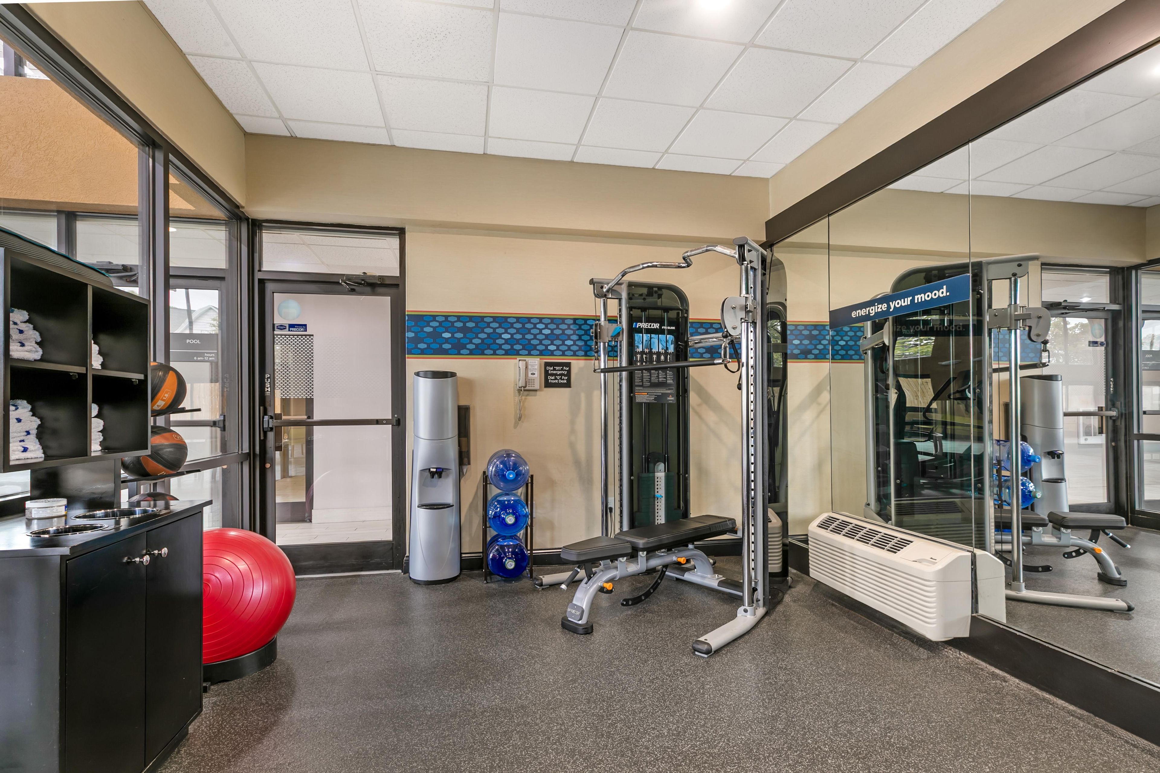 A gym with exercise equipment, a red exercise ball, and a water bottle.