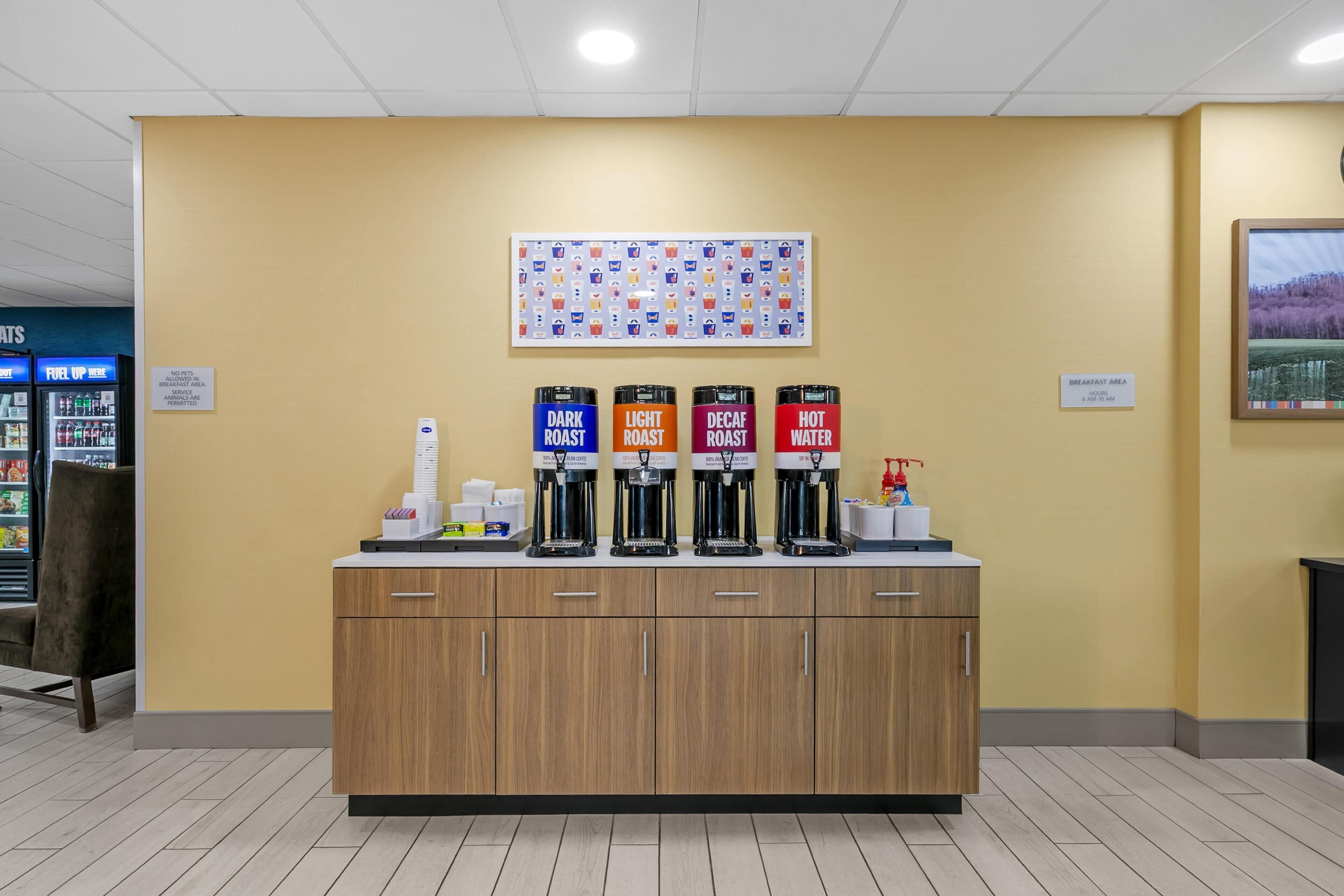 A coffee station with four coffee dispensers labeled 'Dark Roast,' 'Light Roast,' 'Decaf,' and 'Hot Water.'