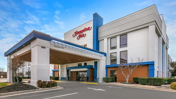 A Hampton Inn hotel with a clear entrance, a gas station, and a 'Welcome' sign.