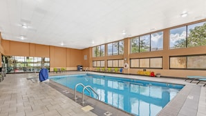 An indoor swimming pool with clear markings, a tiled floor, and large windows.