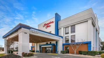 Un hôtel Hampton Inn avec une entrée bien visible, une station-service et une pancarte « Bienvenue ».