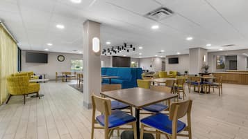 Un espace intérieur vaste et bien aménagé, avec plusieurs coins salon, notamment des tables et des chaises, ainsi qu’un canapé bleu.