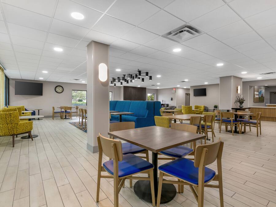A spacious indoor area with multiple seating arrangements, including tables and chairs, and a blue sofa.