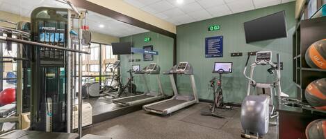 Une salle de sport équipée de tapis de course, de vélos elliptiques et de matériel de musculation.