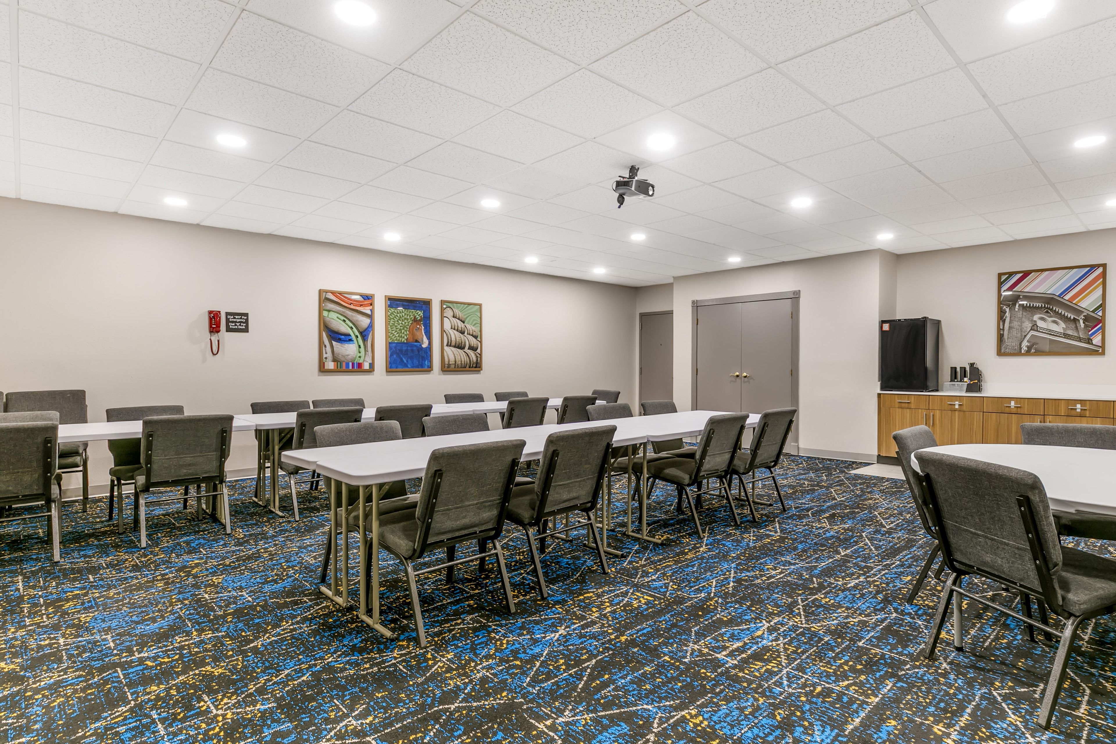 A conference room with tables and chairs, a projector, and artwork on the walls.