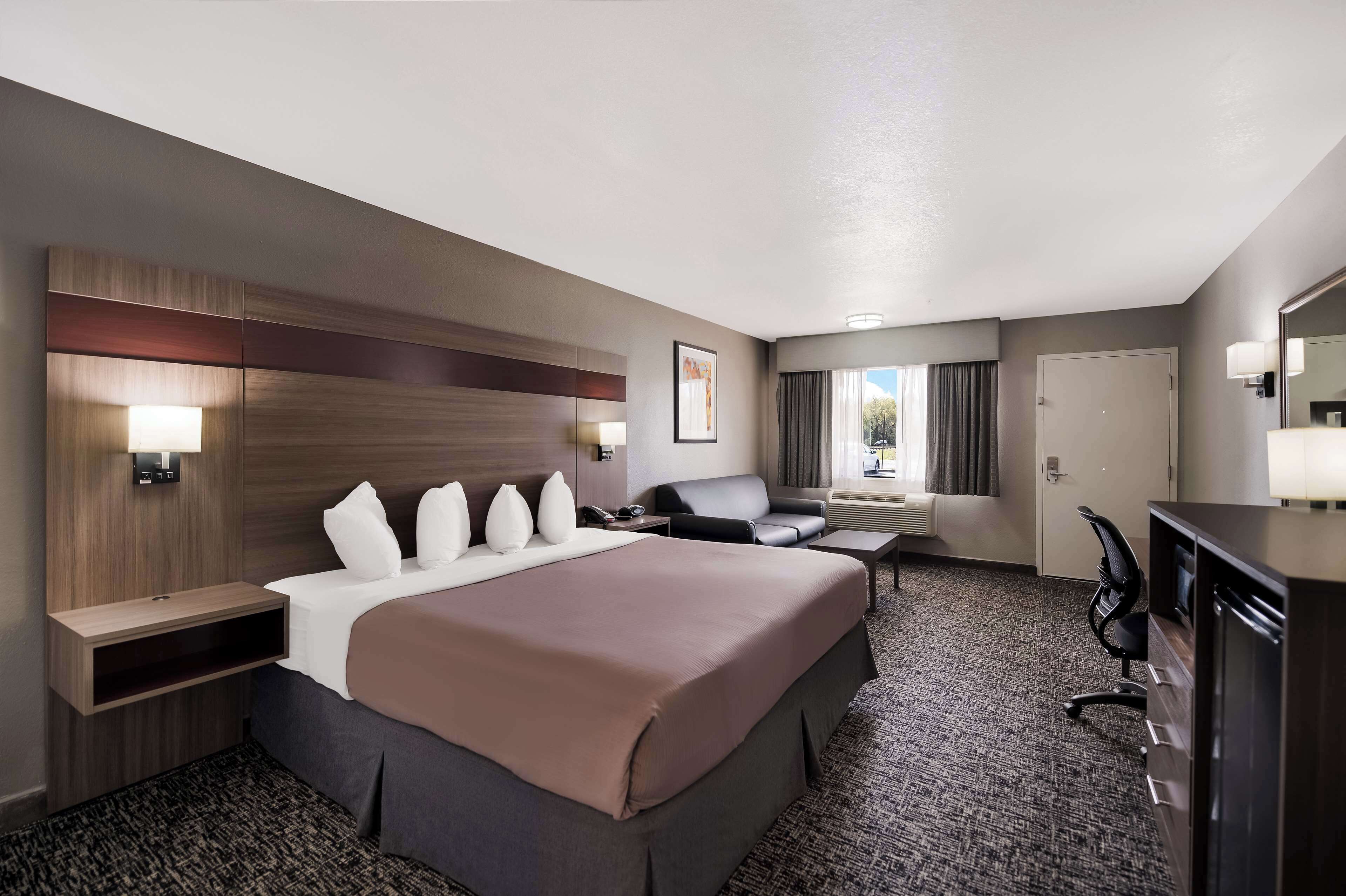 Una habitación de hotel con una cama grande, un escritorio, una silla, un sofá y un baño.