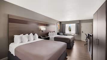 A hotel room with two beds, a desk, a chair, a TV, and a wardrobe.