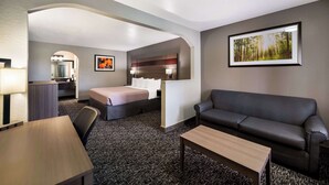Une chambre d’hôtel comprenant un lit, un canapé, un bureau, une chaise, une lampe, un cadre et un miroir.