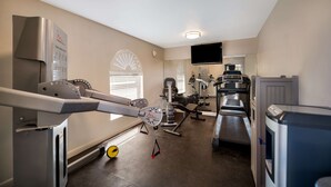 Une salle de sport équipée de matériel d’exercice, d’un téléviseur et d’un miroir.