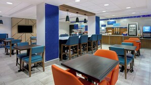 A modern restaurant with blue and orange seating, a flat-screen TV, and a breakfast bar. - Holiday Inn Express Marietta - Atlanta Northwest by IHG (Marietta)