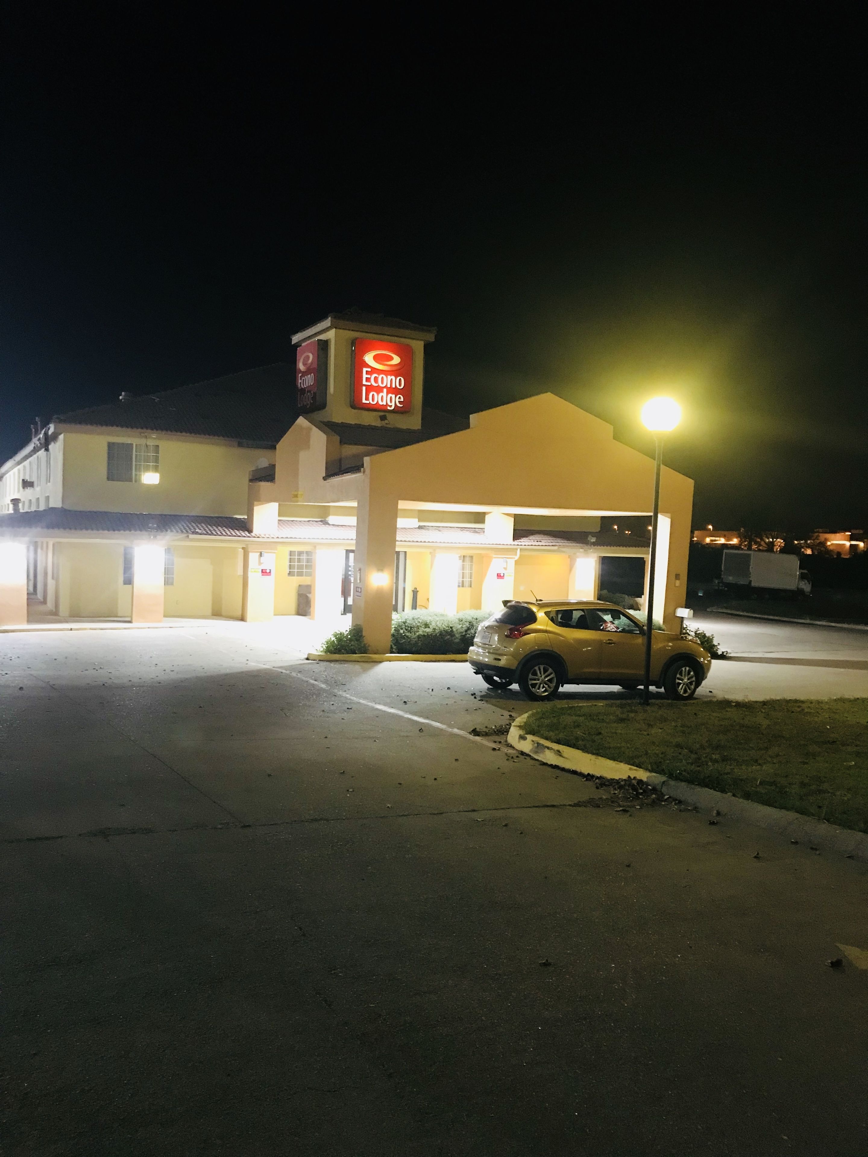 Un hotel llamado Econo Lodge con un coche amarillo estacionado al frente.
