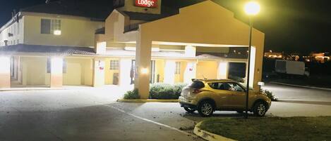 Un hotel llamado Econo Lodge con un coche amarillo estacionado al frente.