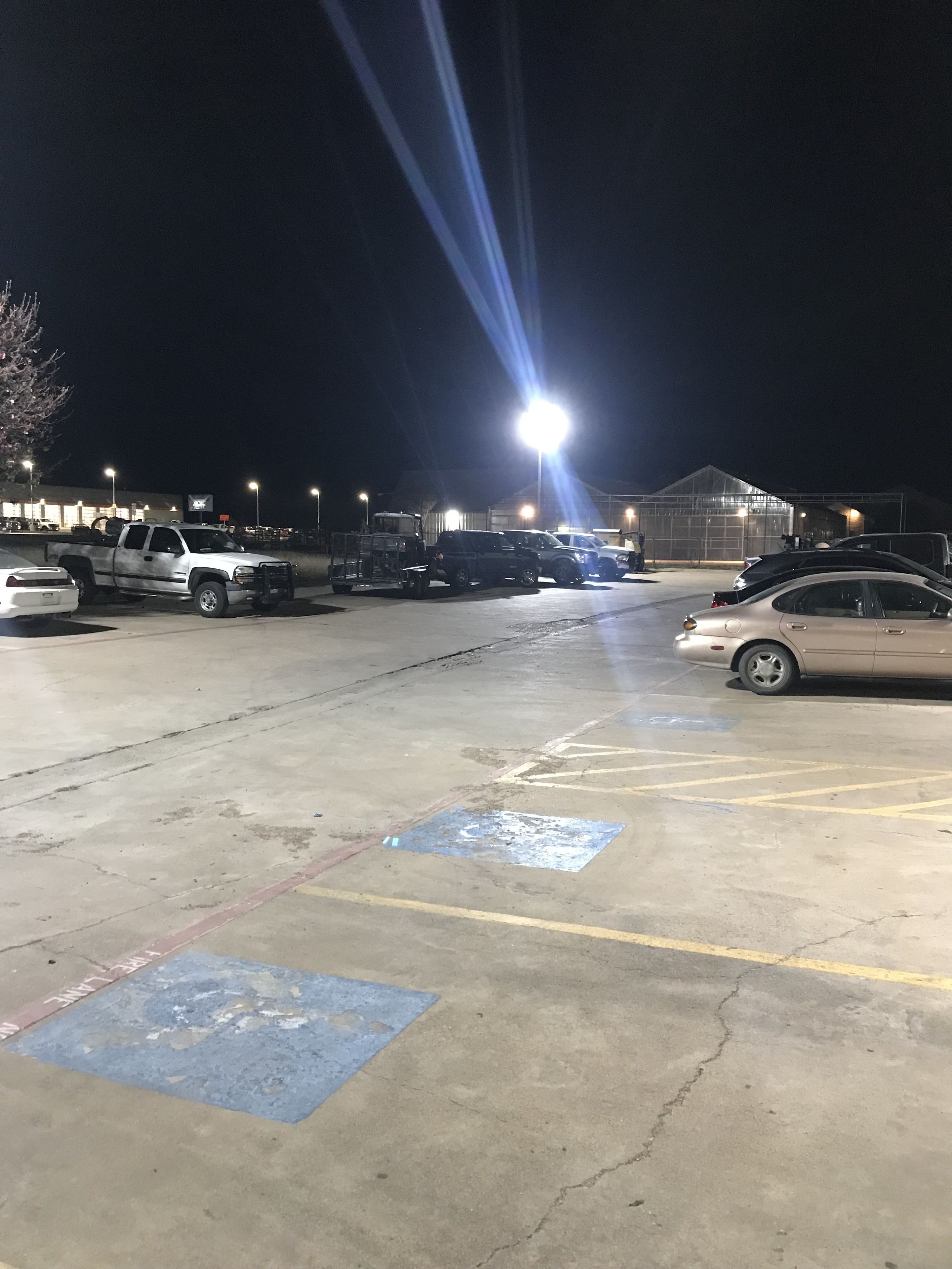 Parcheggio notturno con diversi veicoli, tra cui automobili e camion.