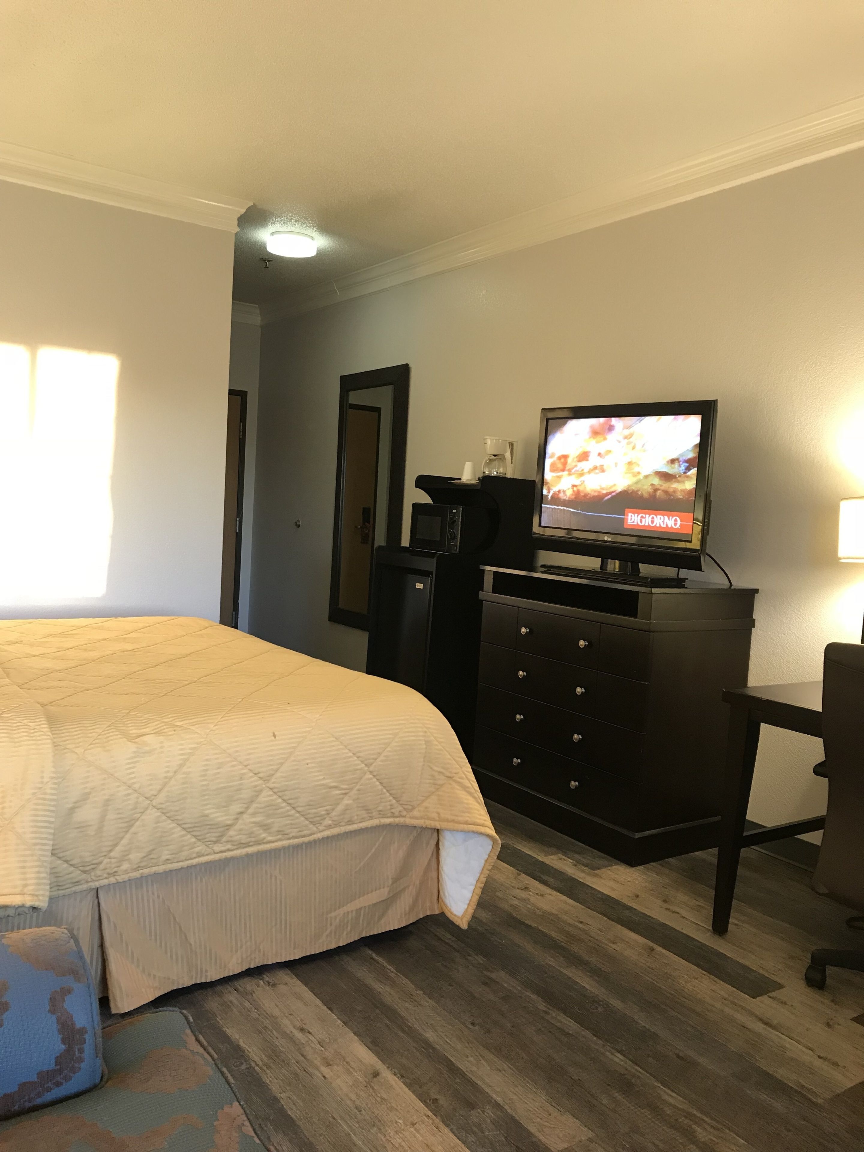 Ett hotellrum med en säng, en byrå, en tv och ett skrivbord.