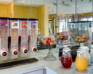 Ein Frühstücksbereich mit Getreideautomaten, Obstschalen und Saftkaraffen.