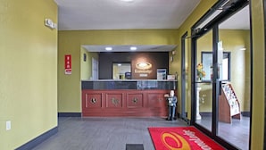 Un área de recepción con alfombra roja, un mostrador de recepción y una estatua.