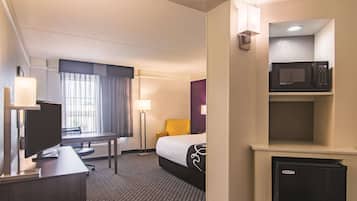 Une chambre d’hôtel équipée d’un lit, d’un bureau, d’une télévision et d’un four à micro-ondes.