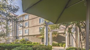 A multi-story building with a covered outdoor area, columns, and a bench. - La Quinta Inn & Suites by Wyndham Oklahoma City Norman (Norman)