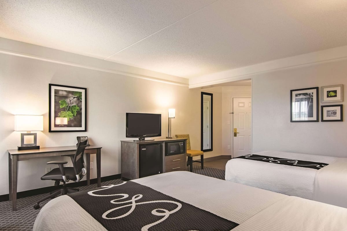 A hotel room with a bed, desk, television, and a mirror.