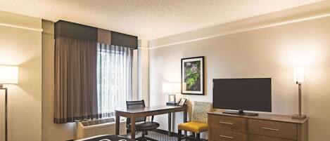 A hotel room with a bed, a desk, a chair, a television, and a dresser.