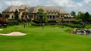 A golf course with a clubhouse and a pond.