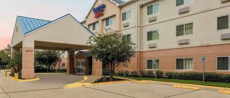 A Fairfield Inn & Suites by Marriott hotel with a covered entrance, multiple floors, and a parking lot.