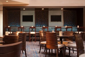 Een restaurant met een behanget patroon, meerdere tafels en stoelen.