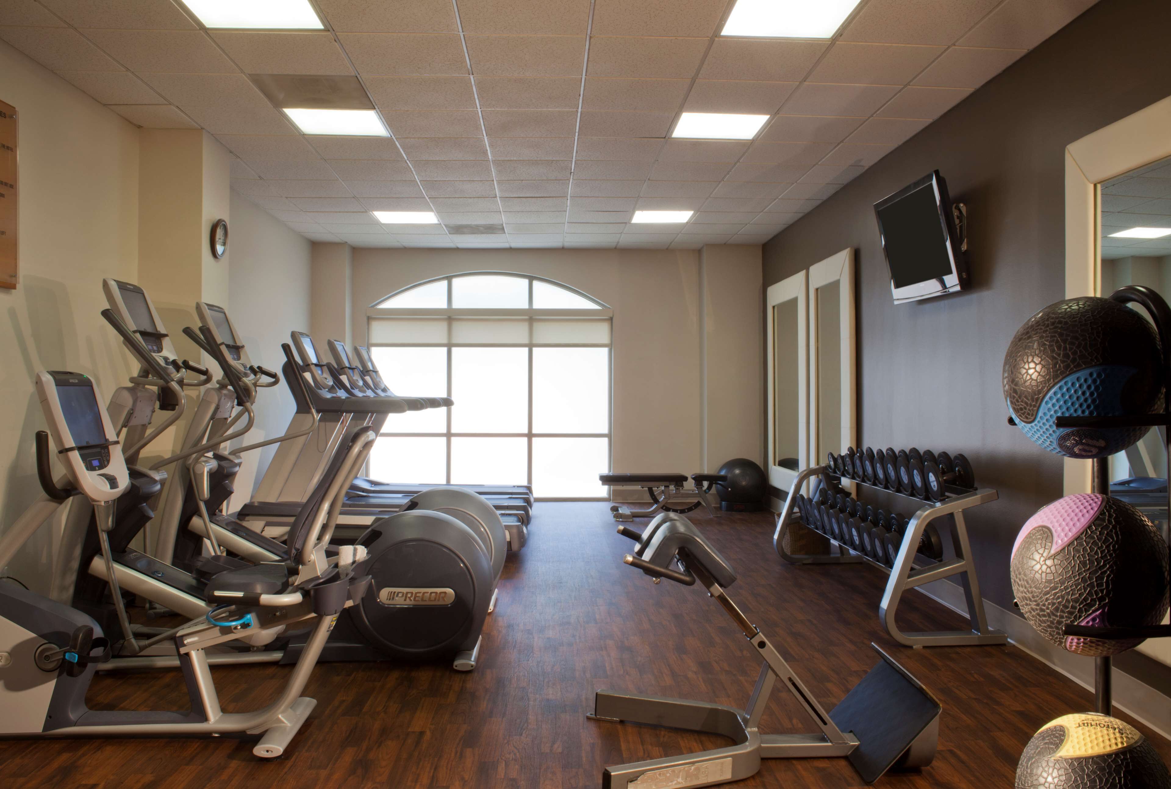 A gym with exercise equipment, a large window, and a wall-mounted TV.