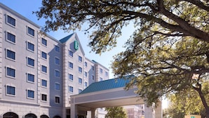 A hotel with a modern design, featuring a covered entrance and a prominent green logo on the building. - Embassy Suites by Hilton Houston Near the Galleria (Houston)