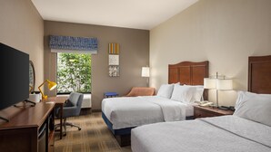 A hotel room with two beds, a desk with a computer, a chair, a TV, and a window with a view of trees. - Hampton Inn Carrollton (Carrollton)