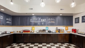 A kitchen with a checkered floor, wooden cabinets, and a chalkboard wall with kitchen-related drawings and text. - Hampton Inn Carrollton (Carrollton)