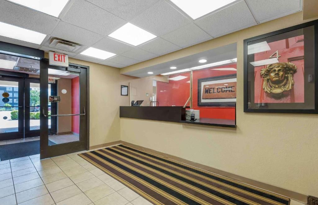 A hotel lobby with an exit sign, a reception desk, and a welcome sign.