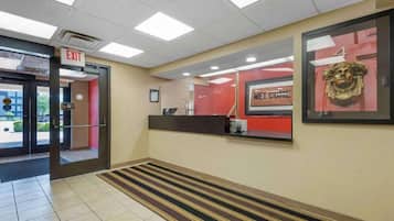 A hotel lobby with an exit sign, a reception desk, and a welcome sign.