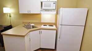 A compact kitchen with white cabinets, a microwave, a stove, and a refrigerator. - Studio 6 Corporate Extended Stay Buffalo Amherst NY (Buffalo)