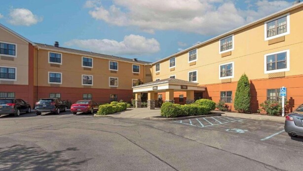 A multi-story hotel with a parking lot, a covered entrance, and a wheelchair-accessible sign. - Studio 6 Corporate Extended Stay Buffalo Amherst NY (Buffalo)