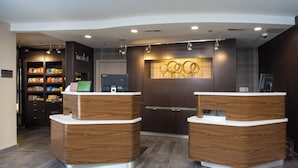 A reception area with two wooden reception desks, a digital screen, and a wall-mounted display. - Courtyard by Marriott Boston Westborough (Westborough)