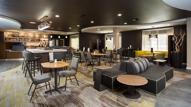 A modern hotel lobby with a bar area, seating arrangements, and a reception desk. - Courtyard by Marriott Boston Westborough (Westborough)