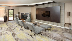 A modern living room with a large flat-screen TV, a sofa set, and a patterned carpet. - Courtyard by Marriott Boston Westborough (Westborough)
