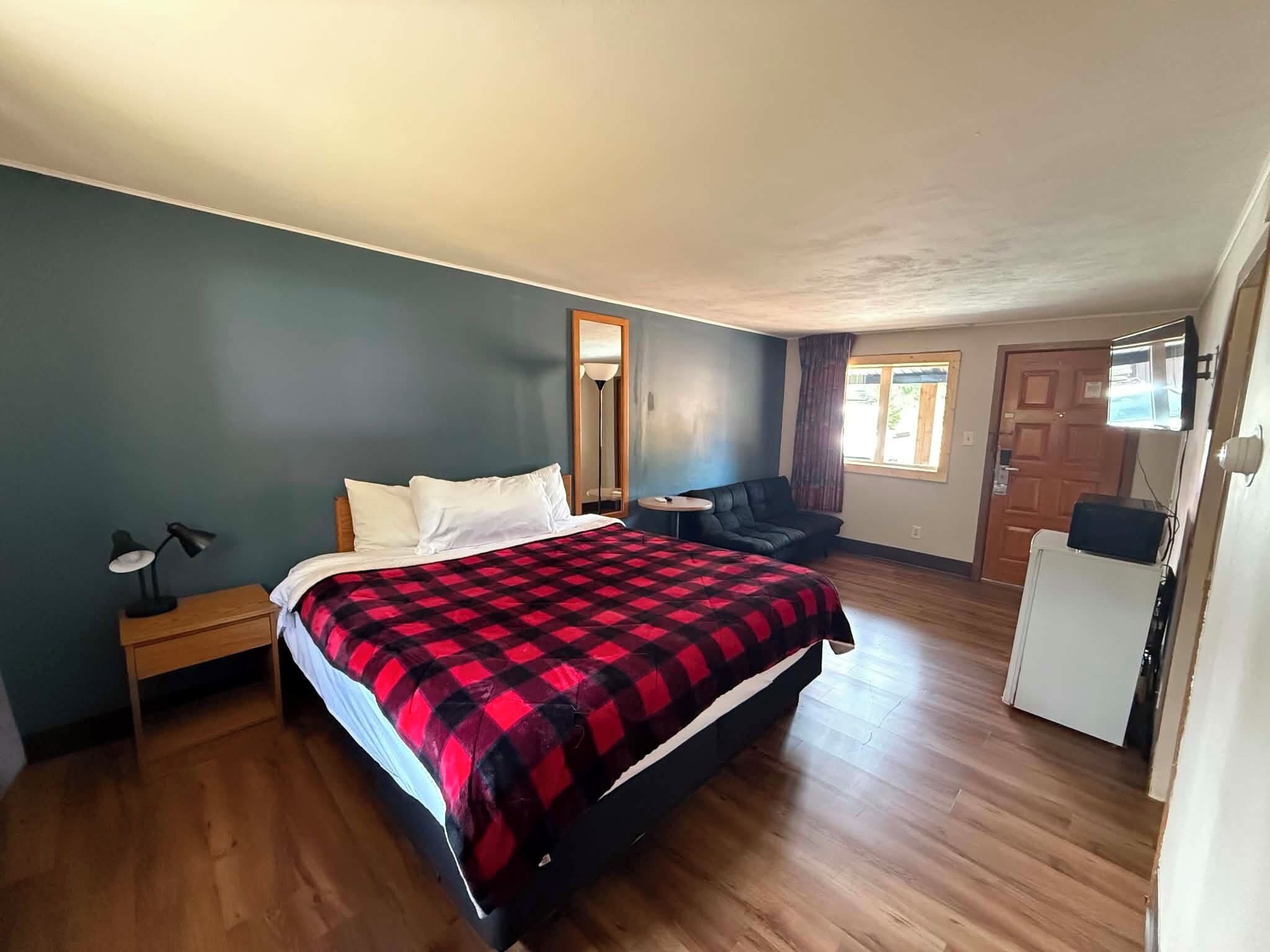 A bedroom with a bed, a chair, a desk, and a window.