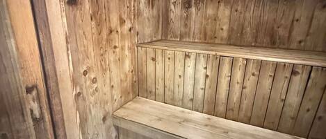 A wooden sauna with benches and a sloped floor.