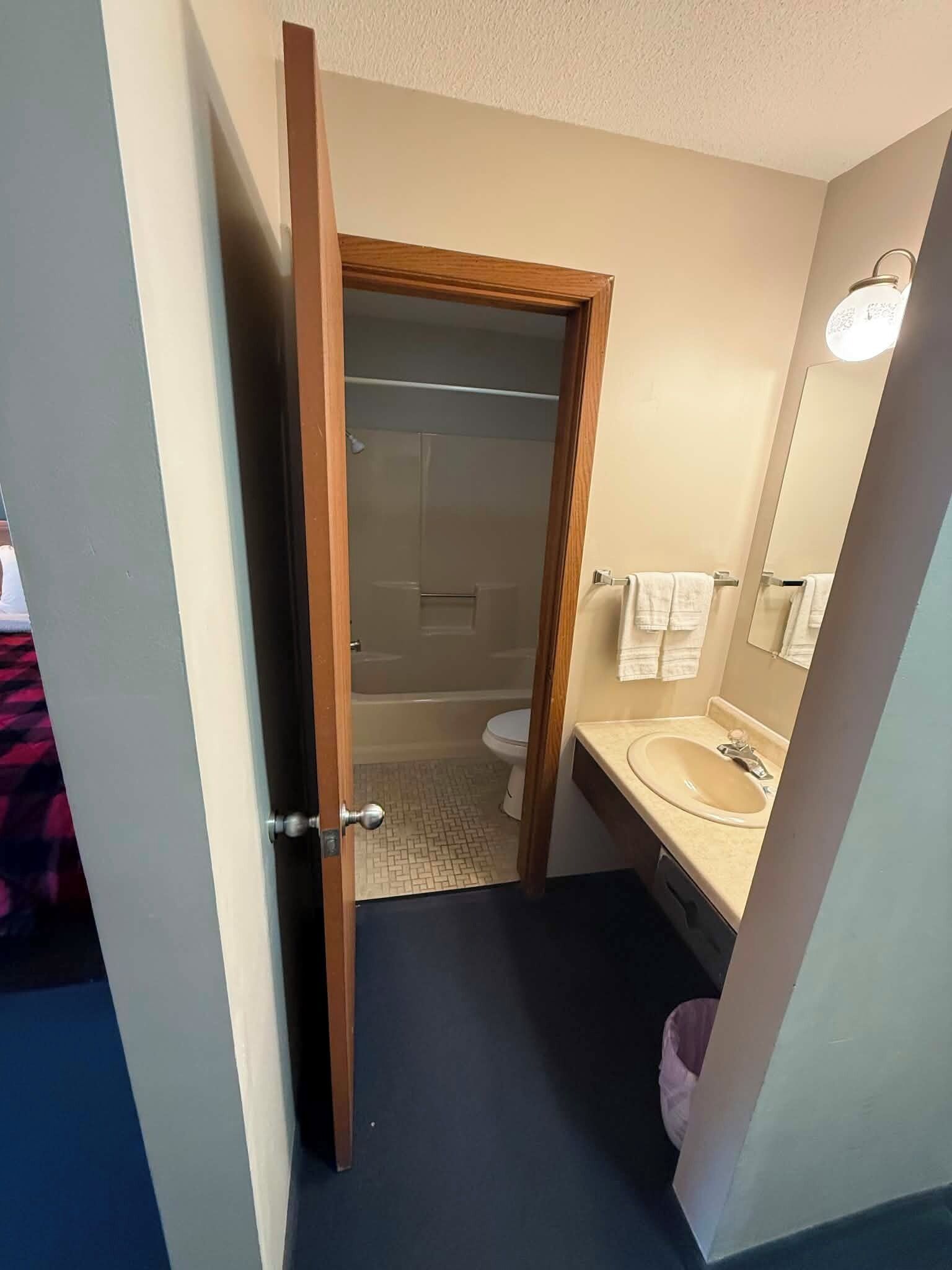 Et badeværelse med bruser, toilet og håndvask.