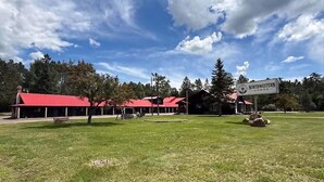 A lodge with a red roof, a sign reading 'Northwestern Lodge,' and a grassy area with trees. - Northwestern Lodge (Hayward)