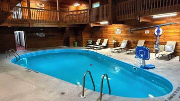 Uma área de piscina com deck de madeira, espreguiçadeiras e posto de salva-vidas.