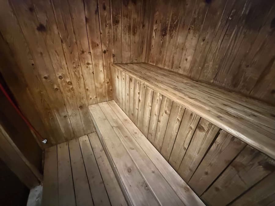 A wooden sauna with benches and a sloped floor.
